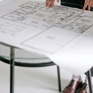 Person examining a detailed architectural floor plan on a table indoors with a focus on design.